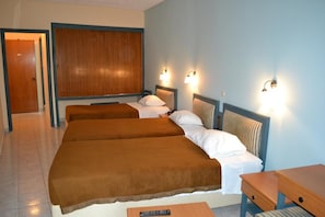 A hotel room with two beds, a wooden headboard, and wall-mounted lights. - Astron (Kos)