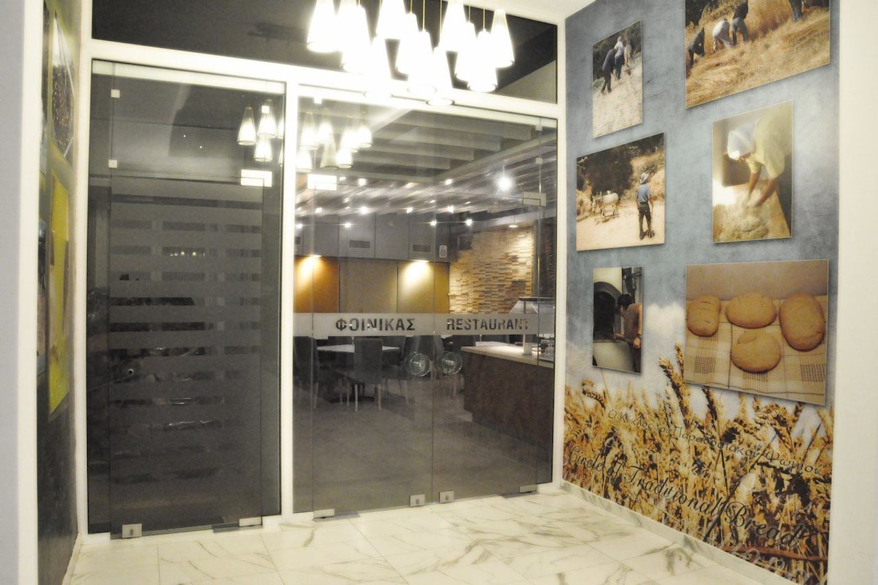 Un restaurant au décor moderne, avec une entrée dotée d’une porte en verre et un mur orné de photographies.