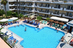 Un hotel amb una gran piscina envoltada de gandules i ombrel·les.