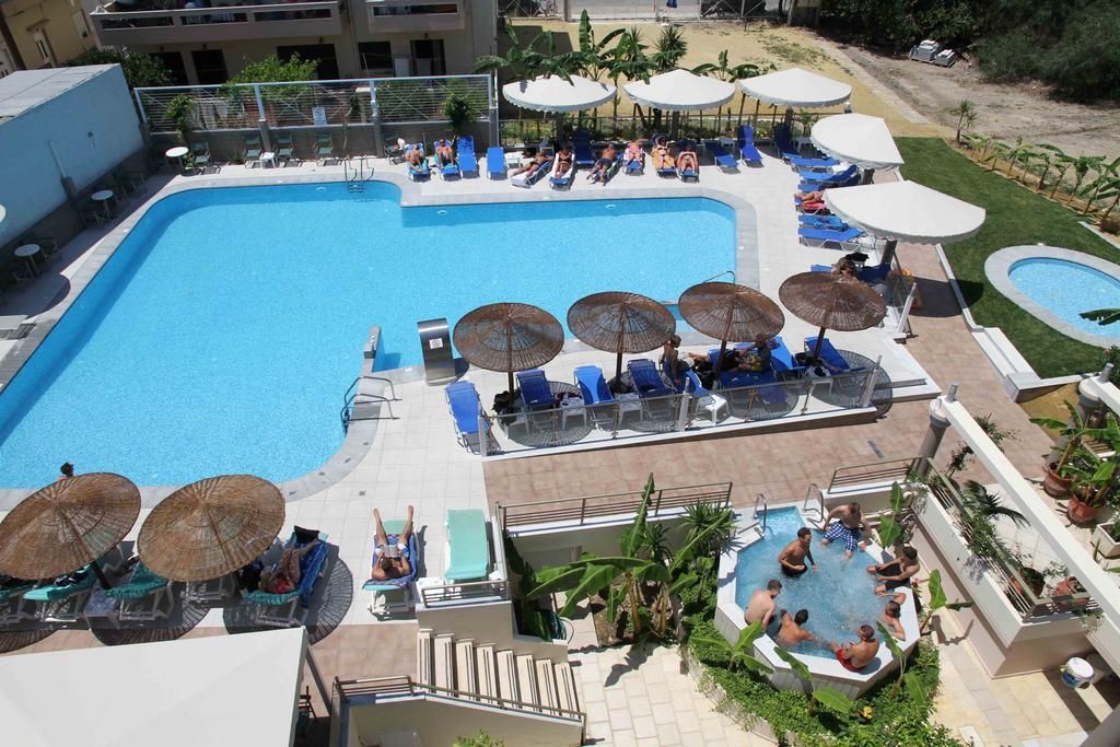 A large outdoor swimming pool with lounge chairs and umbrellas, surrounded by a landscaped area with palm trees.