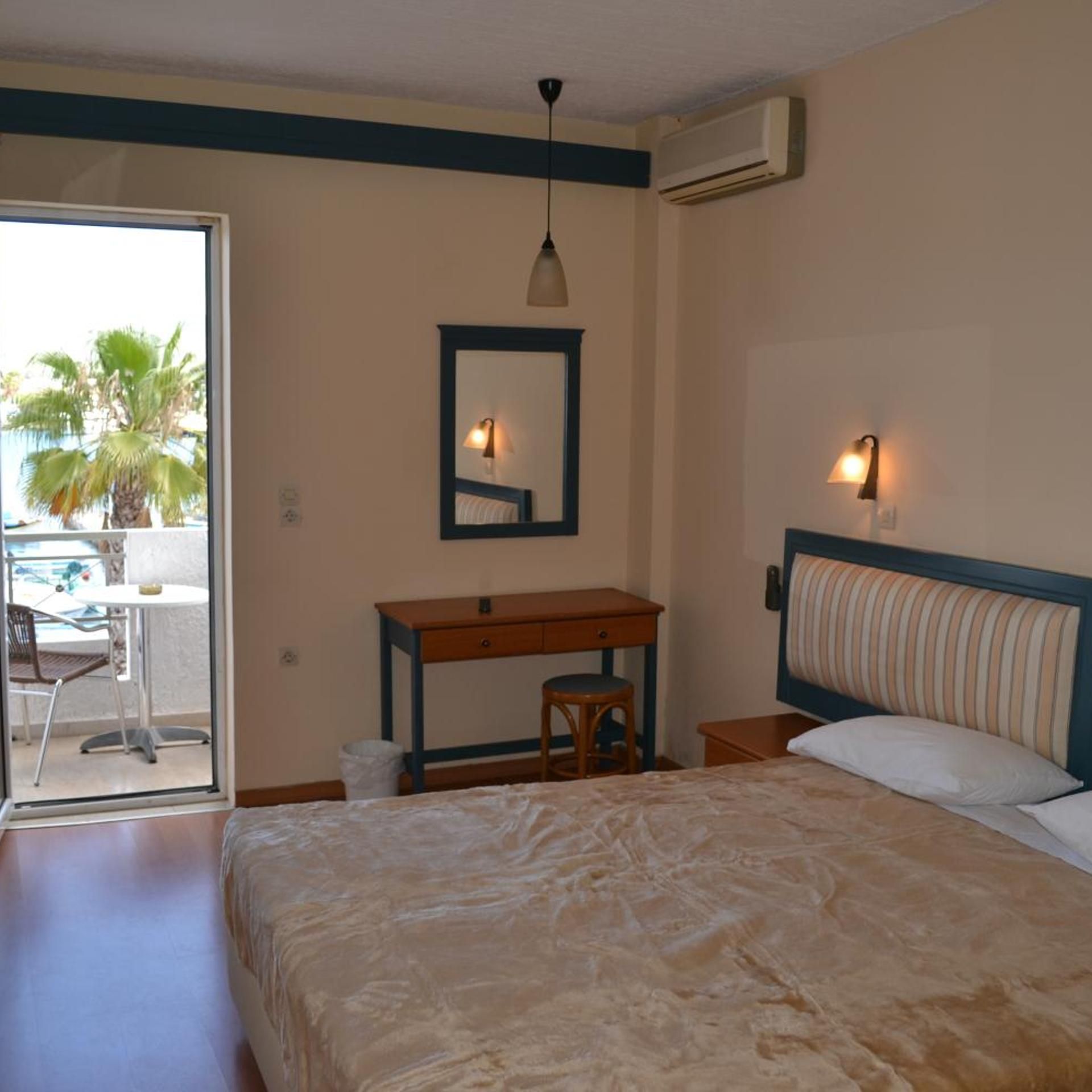Een slaapkamer met een bed, een bureau, een stoel, een spiegel en een airconditioner.