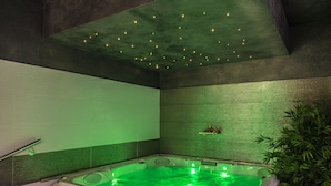 Une salle de spa équipée d’un jacuzzi, d’un éclairage vert et d’une plante.