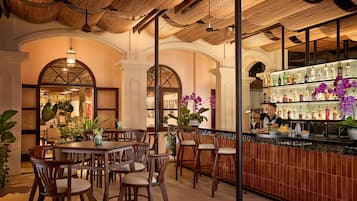 A bar area with wooden furniture, a bartender, and a variety of bottles.