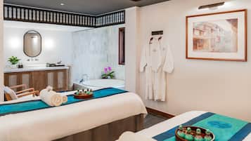 Una habitación de hotel moderna con una cama grande, un área de estar separada, un baño con bañera y un cuadro enmarcado en la pared.