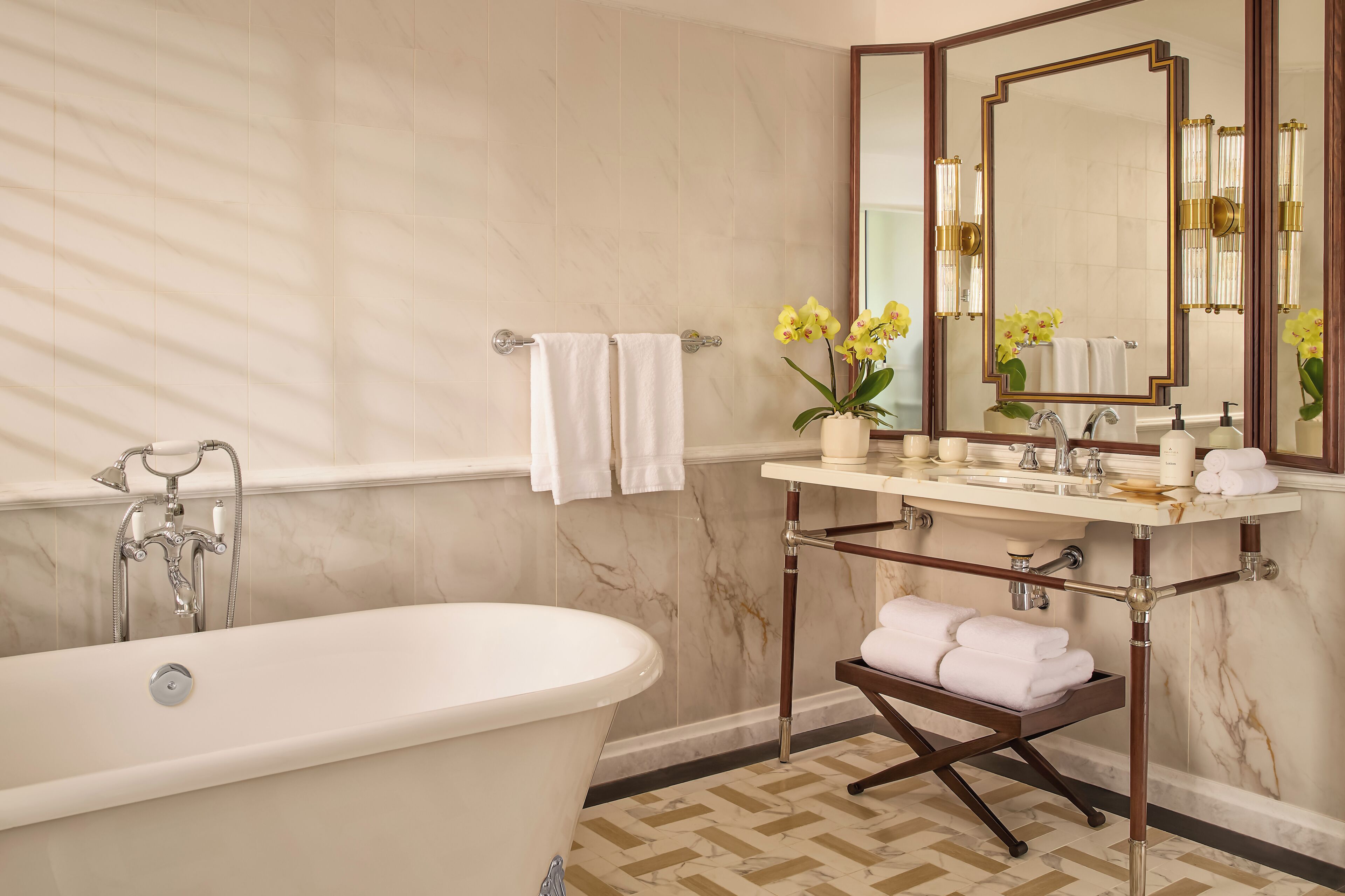 A bathroom with a freestanding bathtub, a vanity with a mirror, and towels.