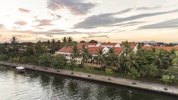A waterfront hotel with a row of villas, a canal, and palm trees.