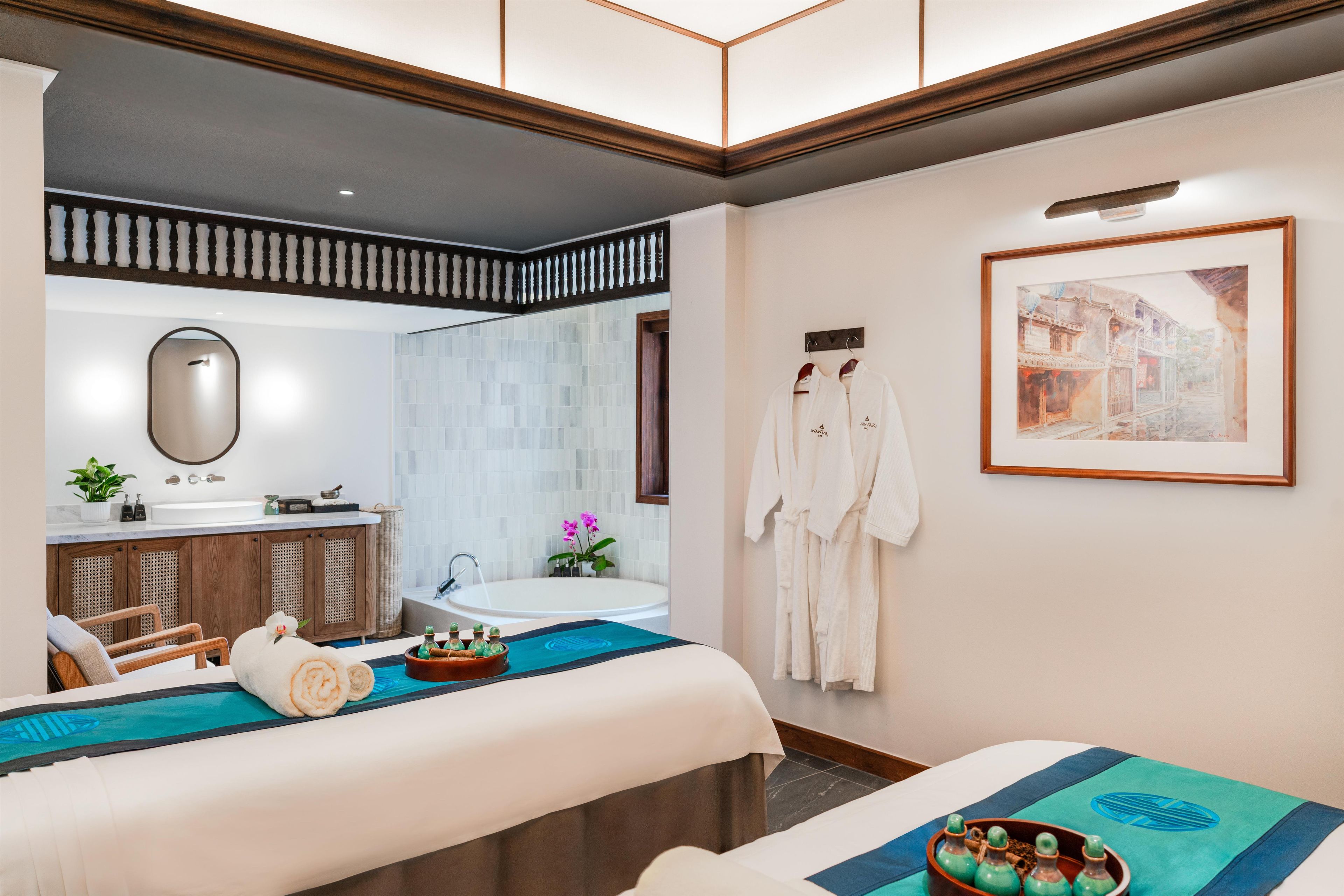 Una habitación de hotel con cama, baño con bañera, espejo y un cuadro en la pared.