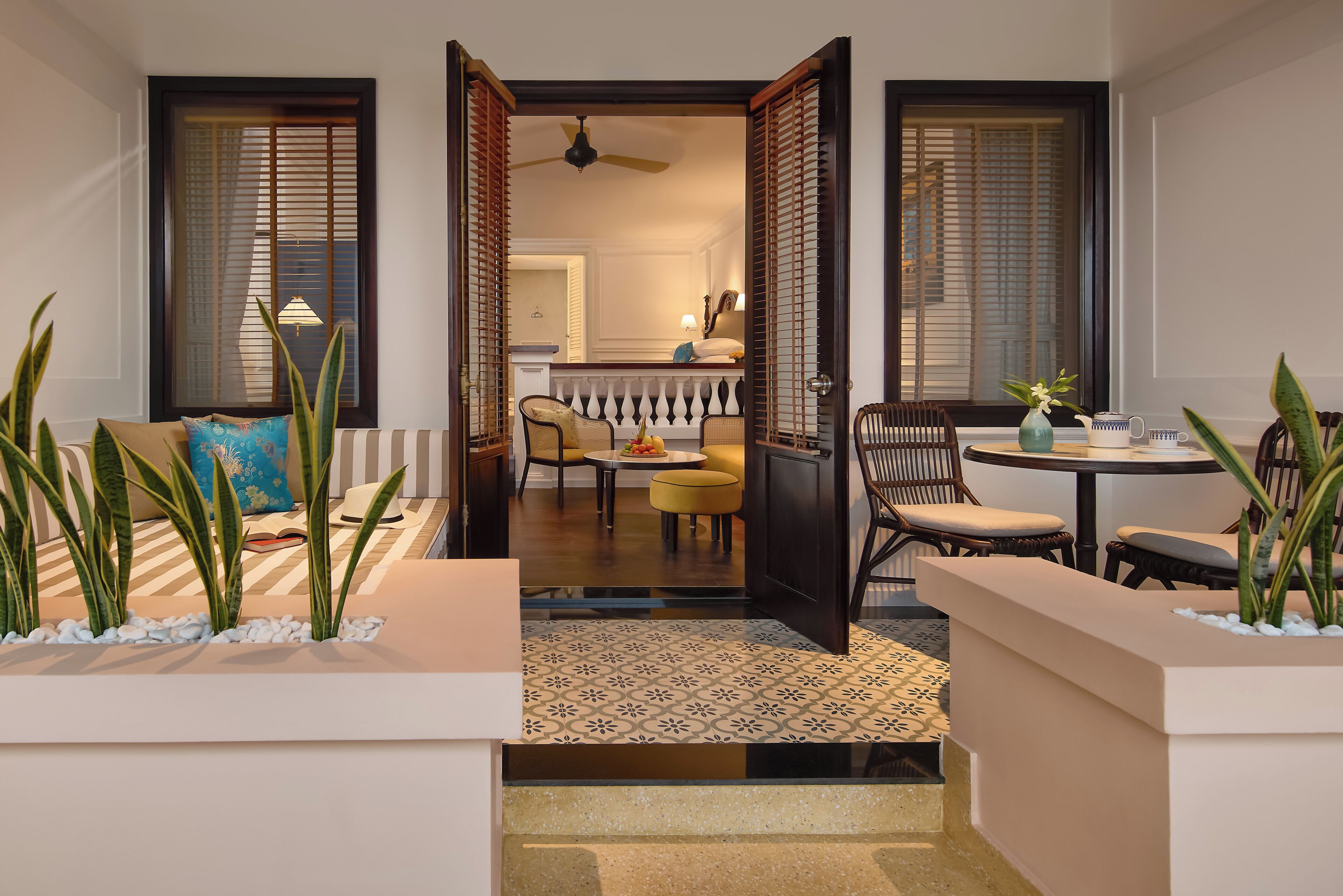 An open doorway leading to a dining area with a ceiling fan, a table with chairs, and a small plant on the side.