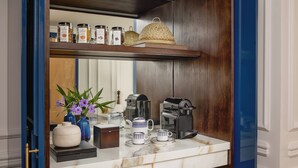 A kitchen counter with a coffee maker, teapot, cups, and jars on a shelf above. - Anantara Hoi An Resort (Da Nang)