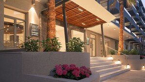 Un hotel moderno con una estructura de varios pisos, zona de estar al aire libre y palmeras.