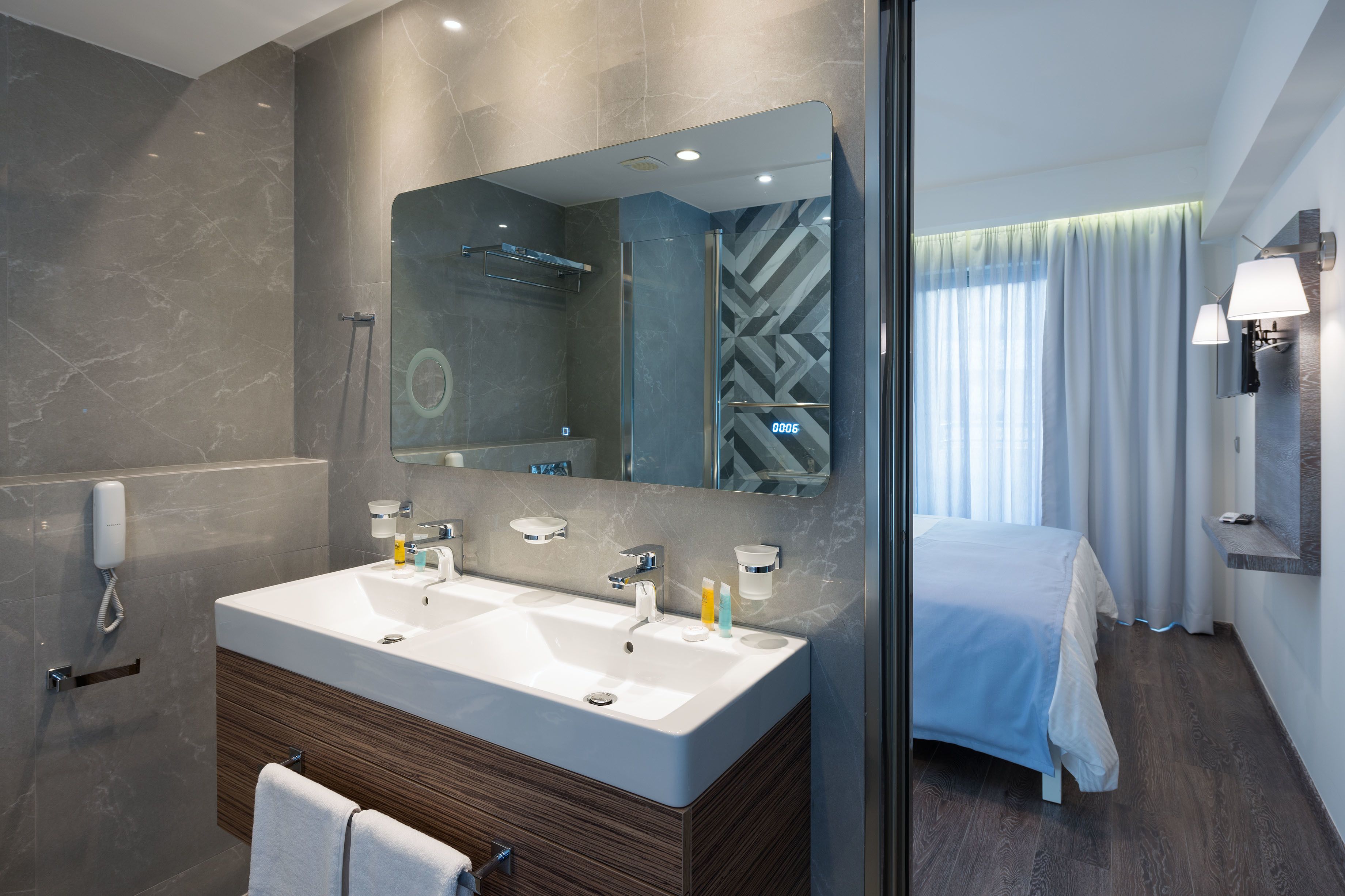 Un baño moderno con un espejo grande, lavamanos dobles y ducha.