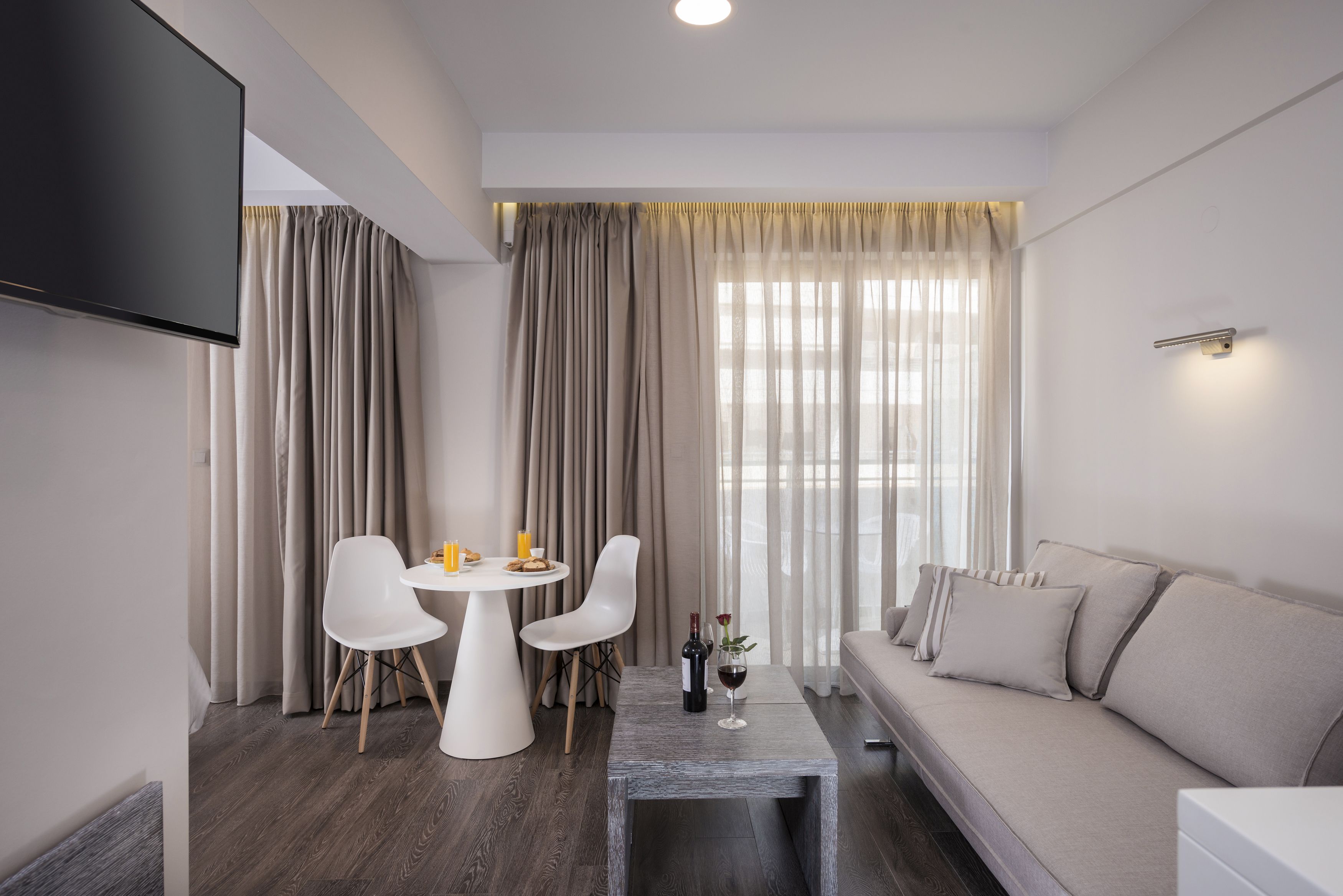 Un salon moderne avec un canapé, une table à manger et des chaises, et un téléviseur fixé au mur.