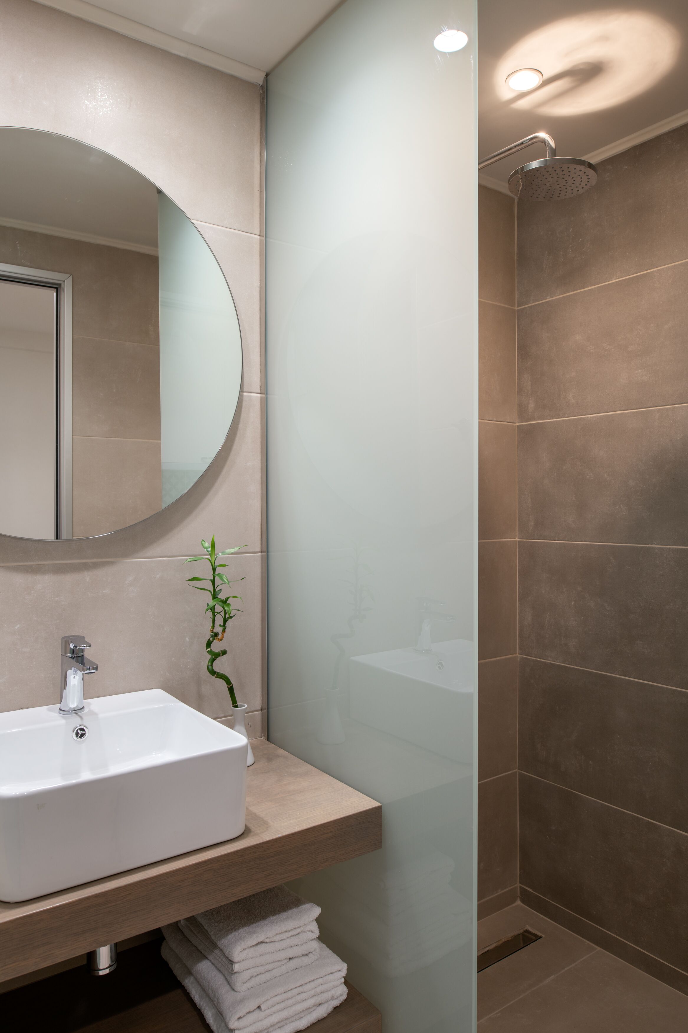 Ein Badezimmer mit Waschbecken, Spiegel, Dusche und Handtuchhalter.