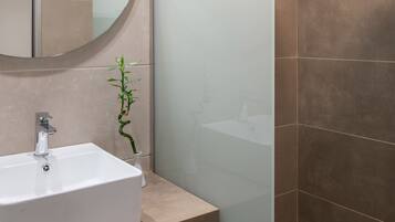 Ein Badezimmer mit Waschbecken, Spiegel, Dusche und Handtuchhalter.