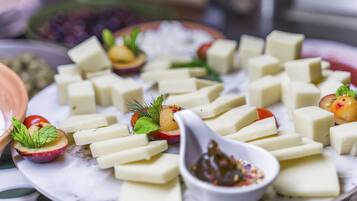 A plate of cheese cubes with garnishes and a small bowl of sauce.