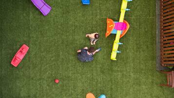 A playground with various play structures on artificial grass.