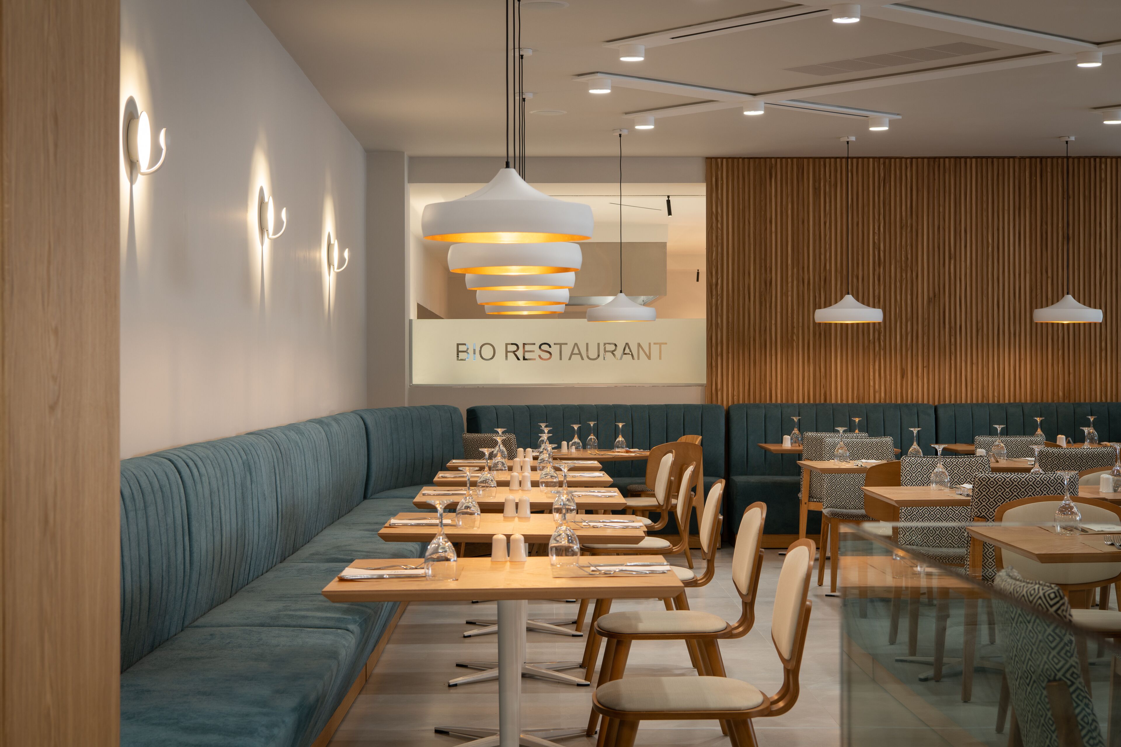 Ein Restaurantinneres mit einer langen Theke, Sitzecken und einer Wand mit Holzverkleidung.