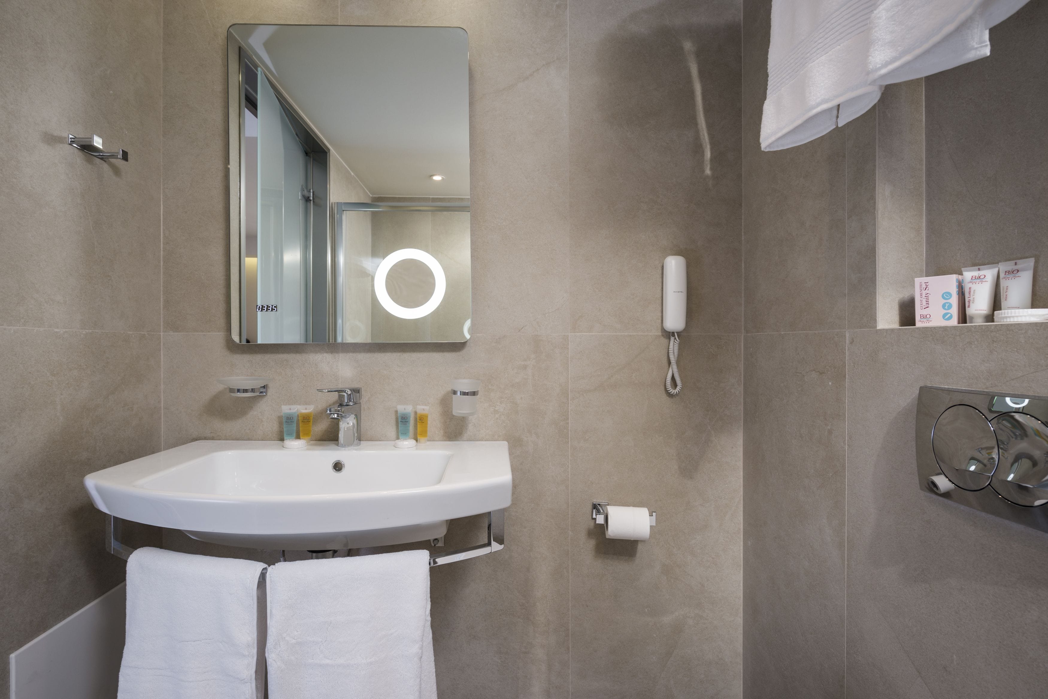 A modern bathroom with a large sink, mirror, and toiletries.