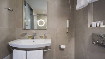 A modern bathroom with a large sink, mirror, and toiletries.