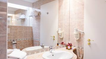 A bathroom with a sink, mirror, towel rack, and a shower area.
