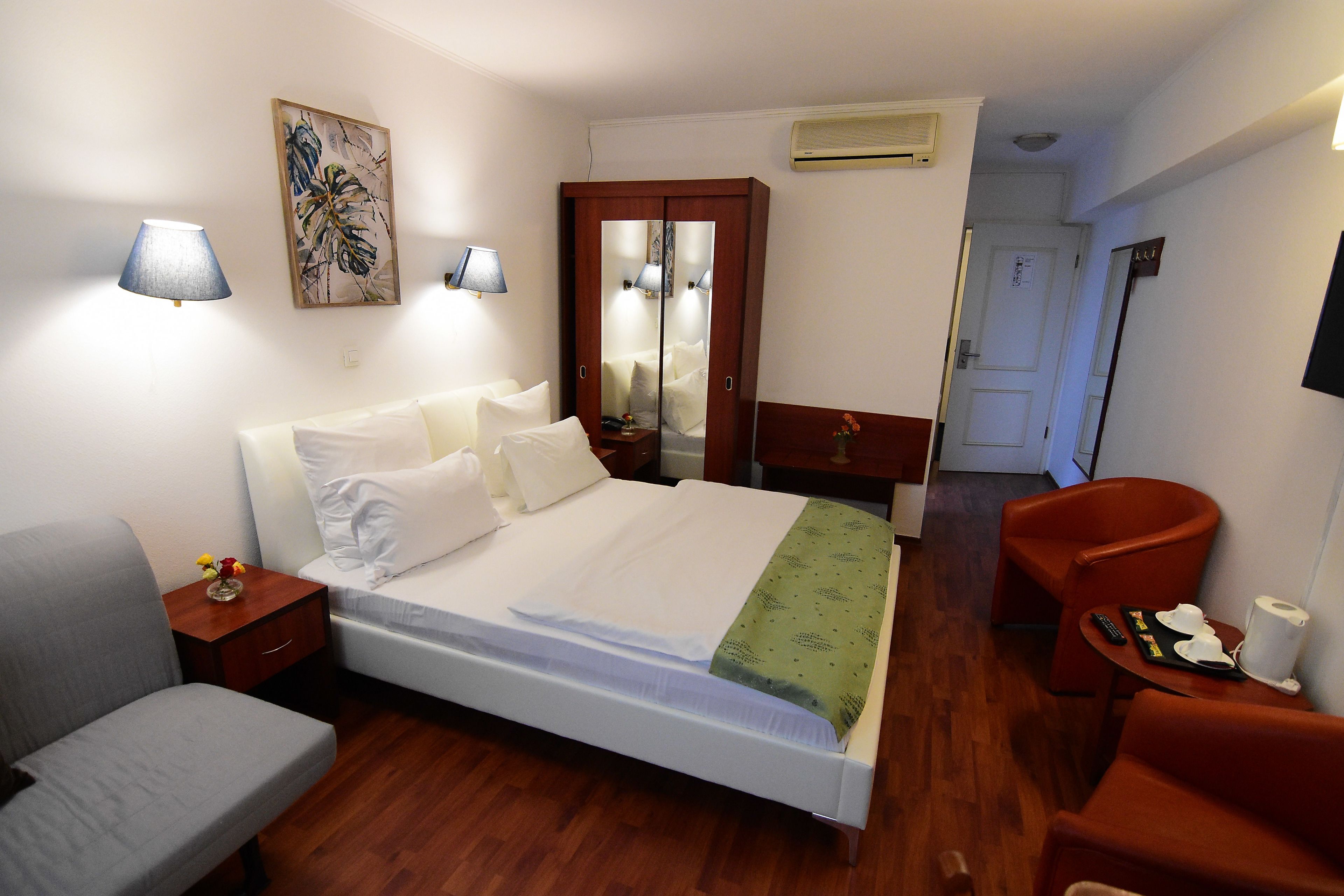 Una habitación de hotel con una cama, una silla, un escritorio y un espejo.