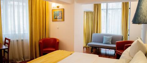 Una habitación de hotel con una cama, dos sillas, un sofá y un cuadro en la pared.