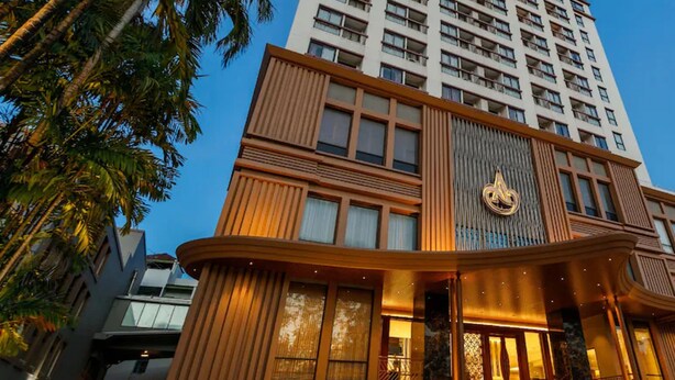 A modern hotel with a prominent entrance, multiple floors, and a view of palm trees. - Amora Hotel Tapae Chiang Mai (Chiang Mai)