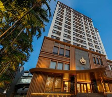 A modern hotel with a prominent entrance, multiple floors, and a view of palm trees.