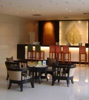 A lobby with a reception desk, several chairs, a round table, and a decorative wall piece.