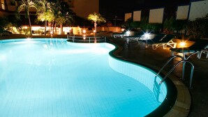 A swimming pool with a tiled edge and a surrounding deck area with lounge chairs and a palm tree. - Amora Hotel Tapae Chiang Mai (Chiang Mai)