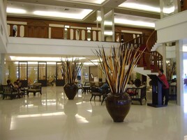 A spacious lobby with a high ceiling, a staircase, and seating areas.