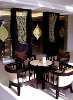 A modern lounge area with a round table and four chairs, surrounded by decorative panels with intricate designs.