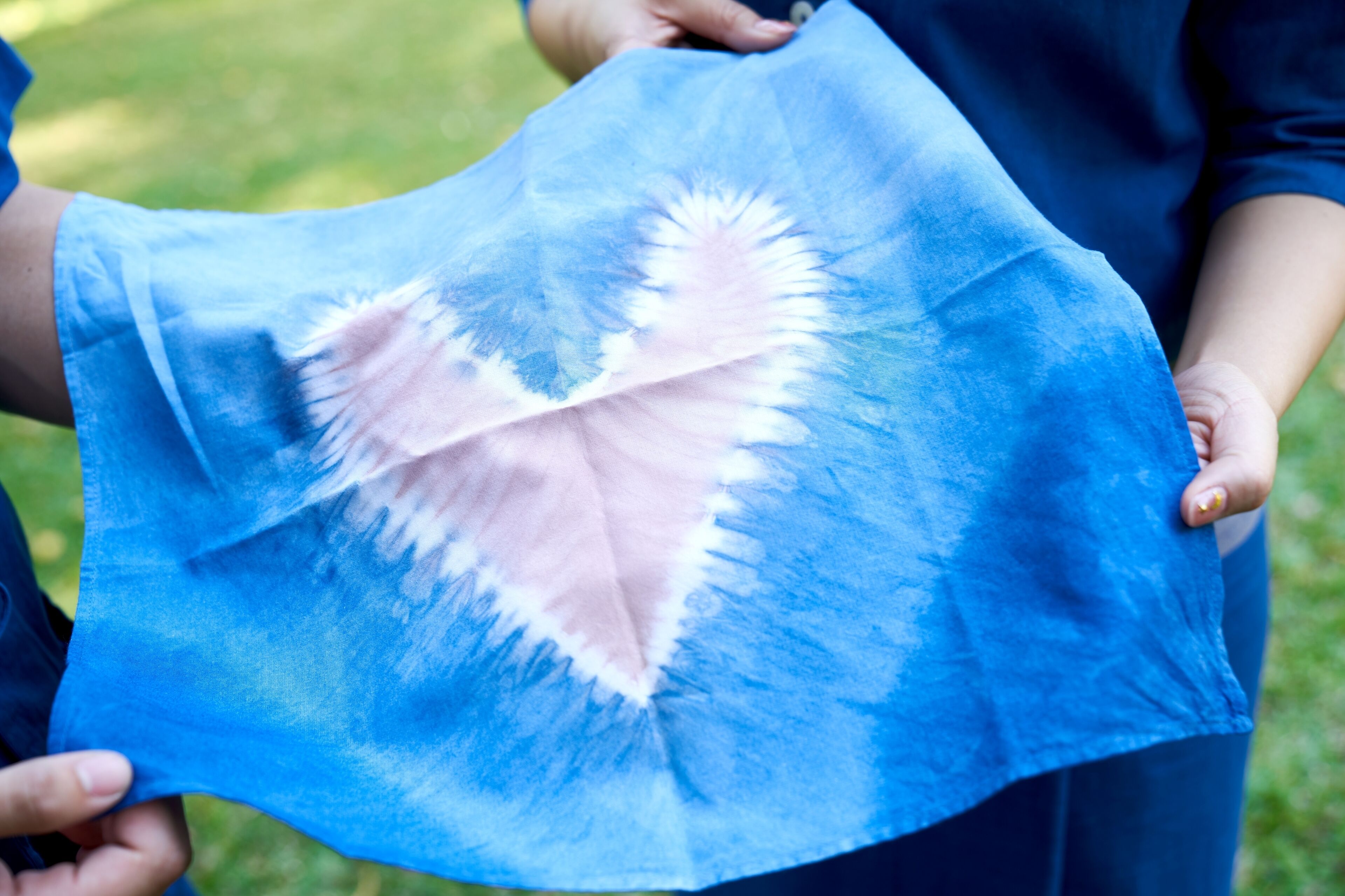 Una persona sosteniendo un tejido azul con un diseño de corazón.