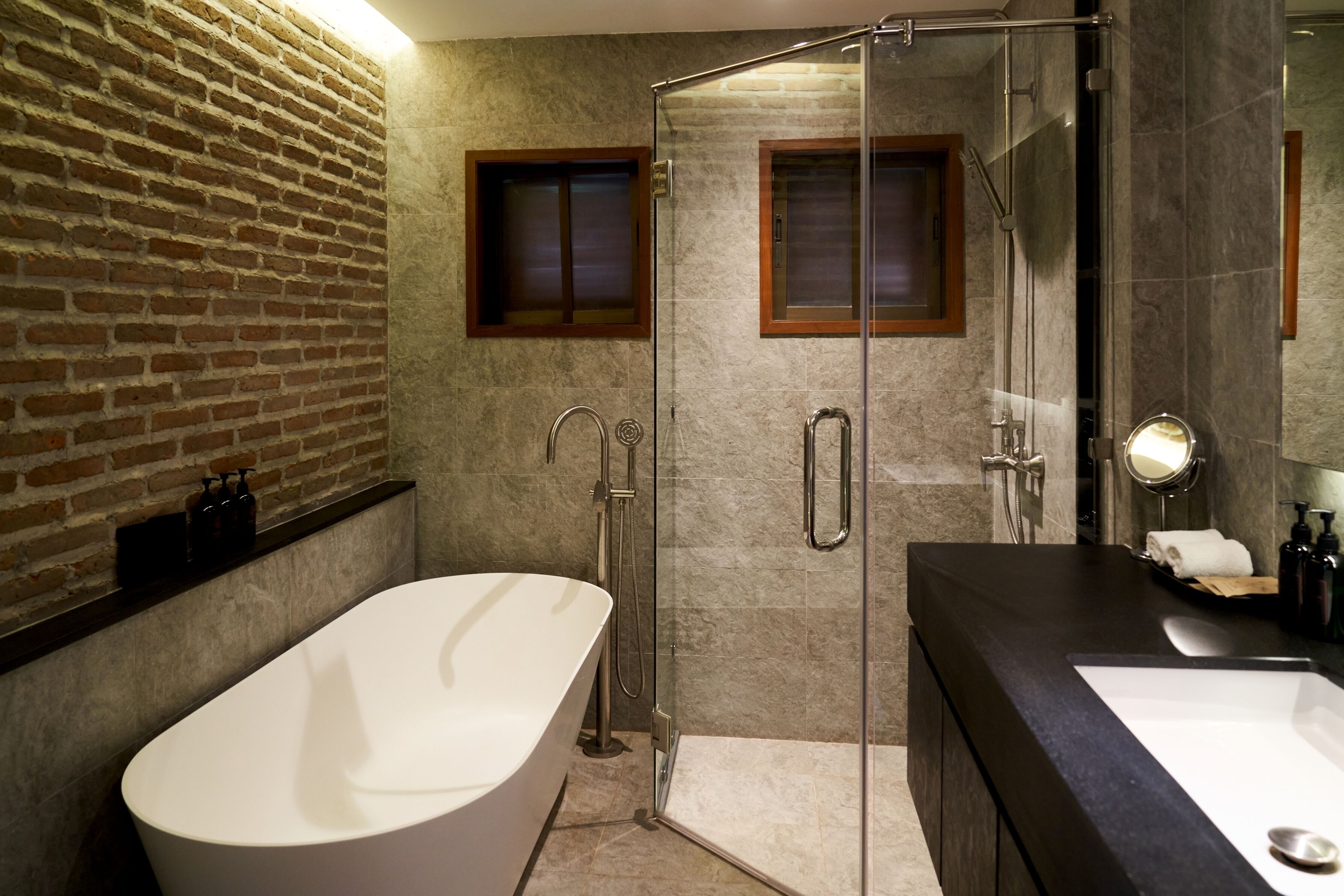 A modern bathroom with a freestanding bathtub, a glass-enclosed shower, and a dark countertop sink.