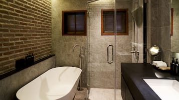A modern bathroom with a freestanding bathtub, a glass-enclosed shower, and a dark countertop sink.