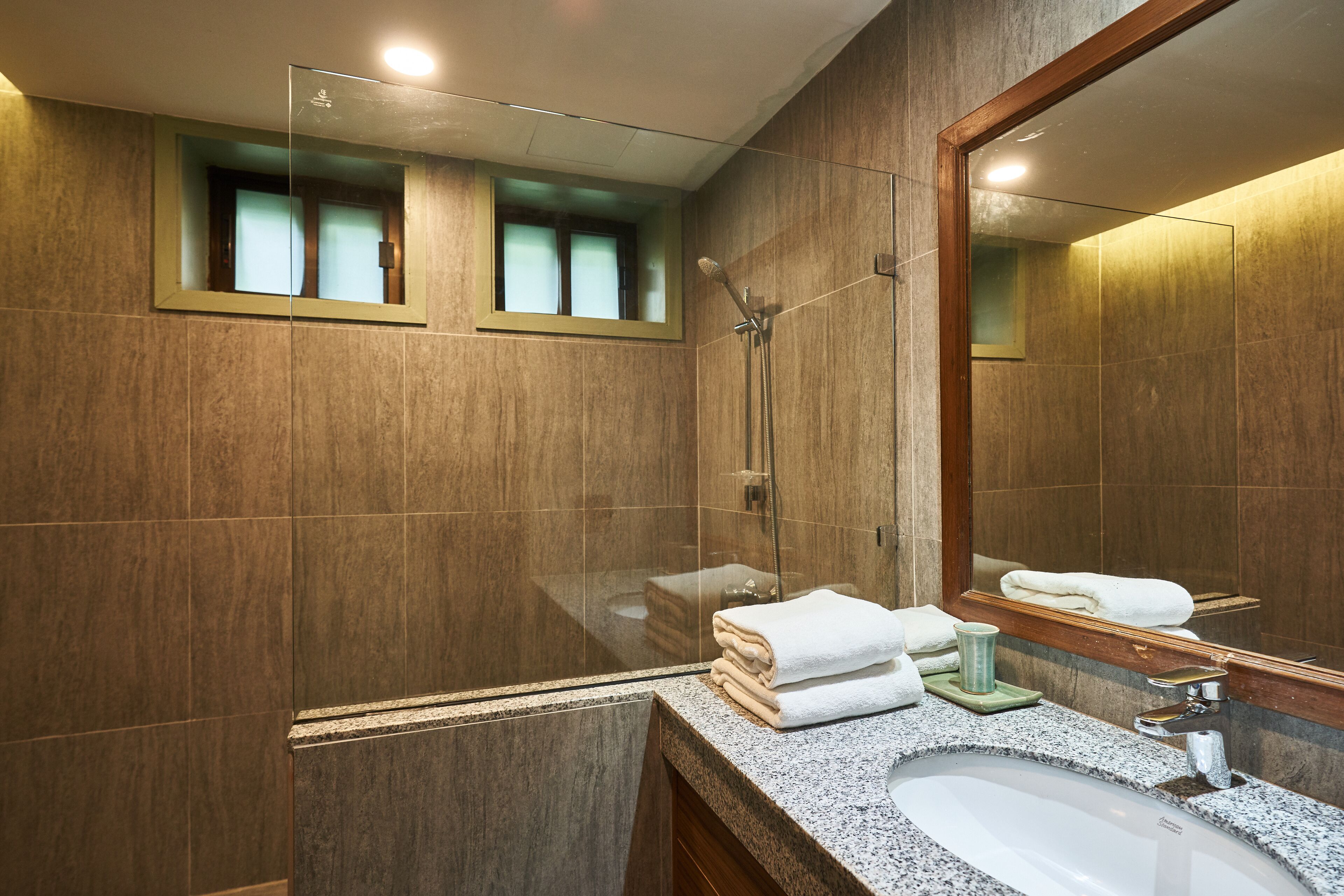 A modern bathroom with a granite countertop, a sink, a mirror, and a shower.