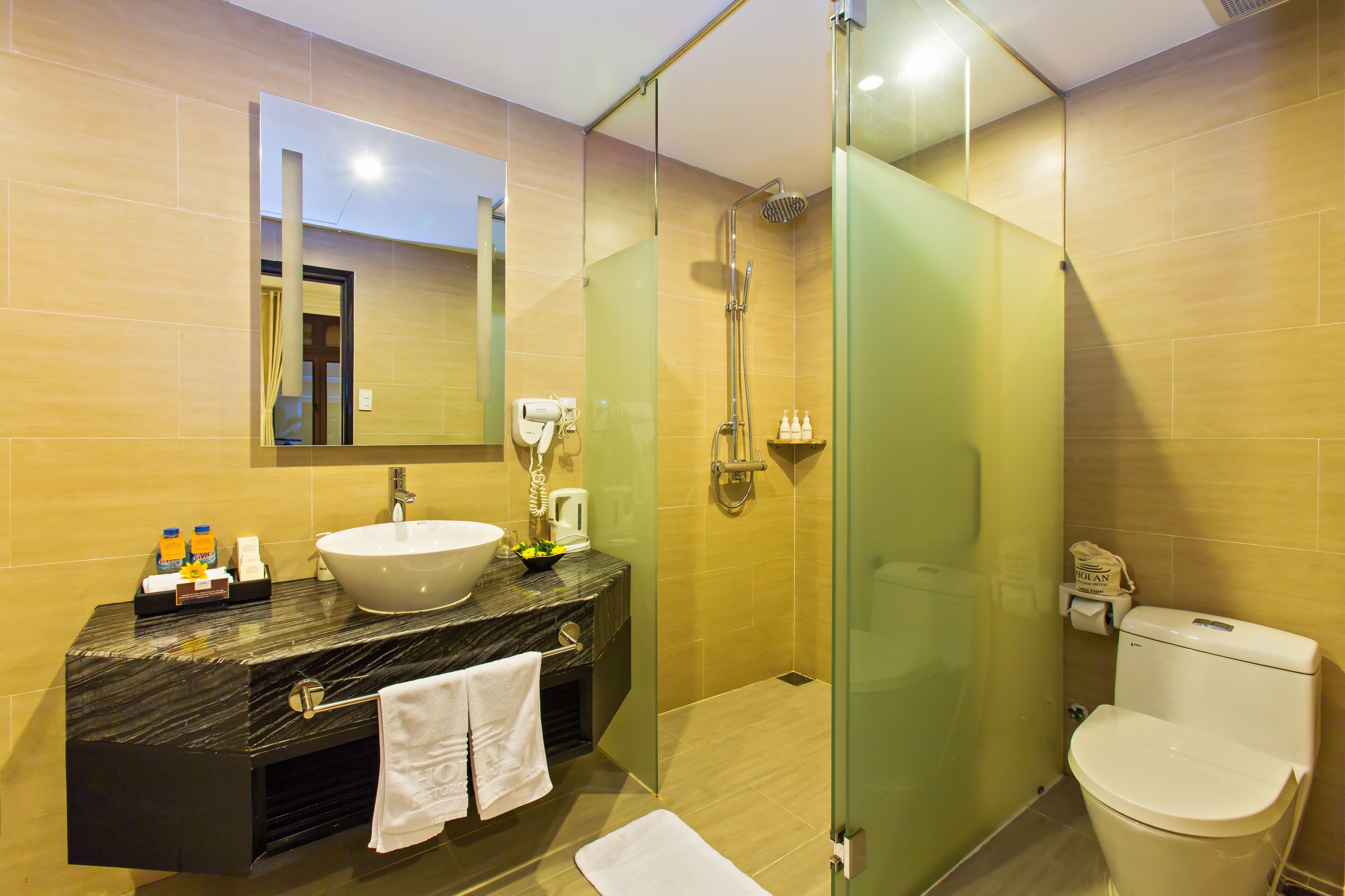 A modern bathroom with a marble sink, a glass-enclosed shower, and a toilet.