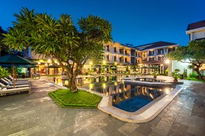 A pool area with lounge chairs, a small pond, and a building with multiple balconies. - Hoi An Historic Hotel (Da Nang)