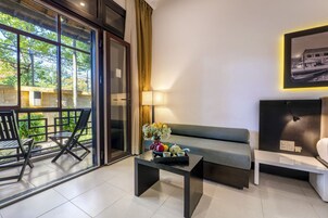 Una sala de estar moderna con un sofá, una mesa de centro y un área de comedor con sillas. Hay un ventanal con cortinas, una lámpara y un cuadro en la pared.