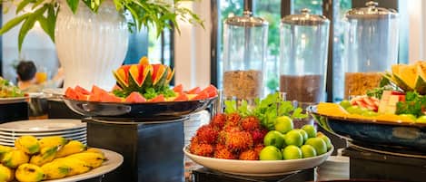 A buffet with various fruits and vegetables, including bananas, passion fruit, and watermelon.