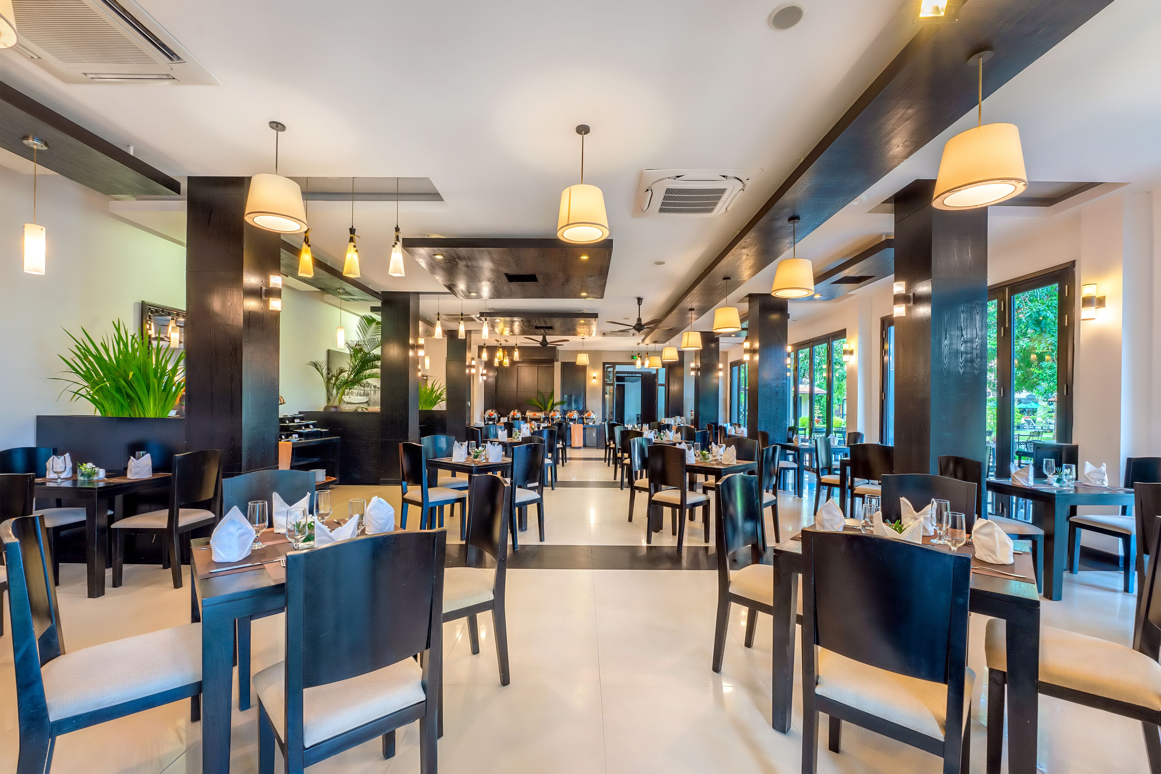 A spacious restaurant with high ceilings, pendant lighting, and a modern interior design.