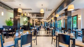 Een ruim restaurant met hoge plafonds, hanglampen en een modern interieur.