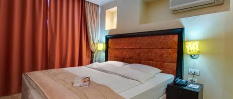 A hotel room with a bed, nightstand, and a wall-mounted air conditioner.
