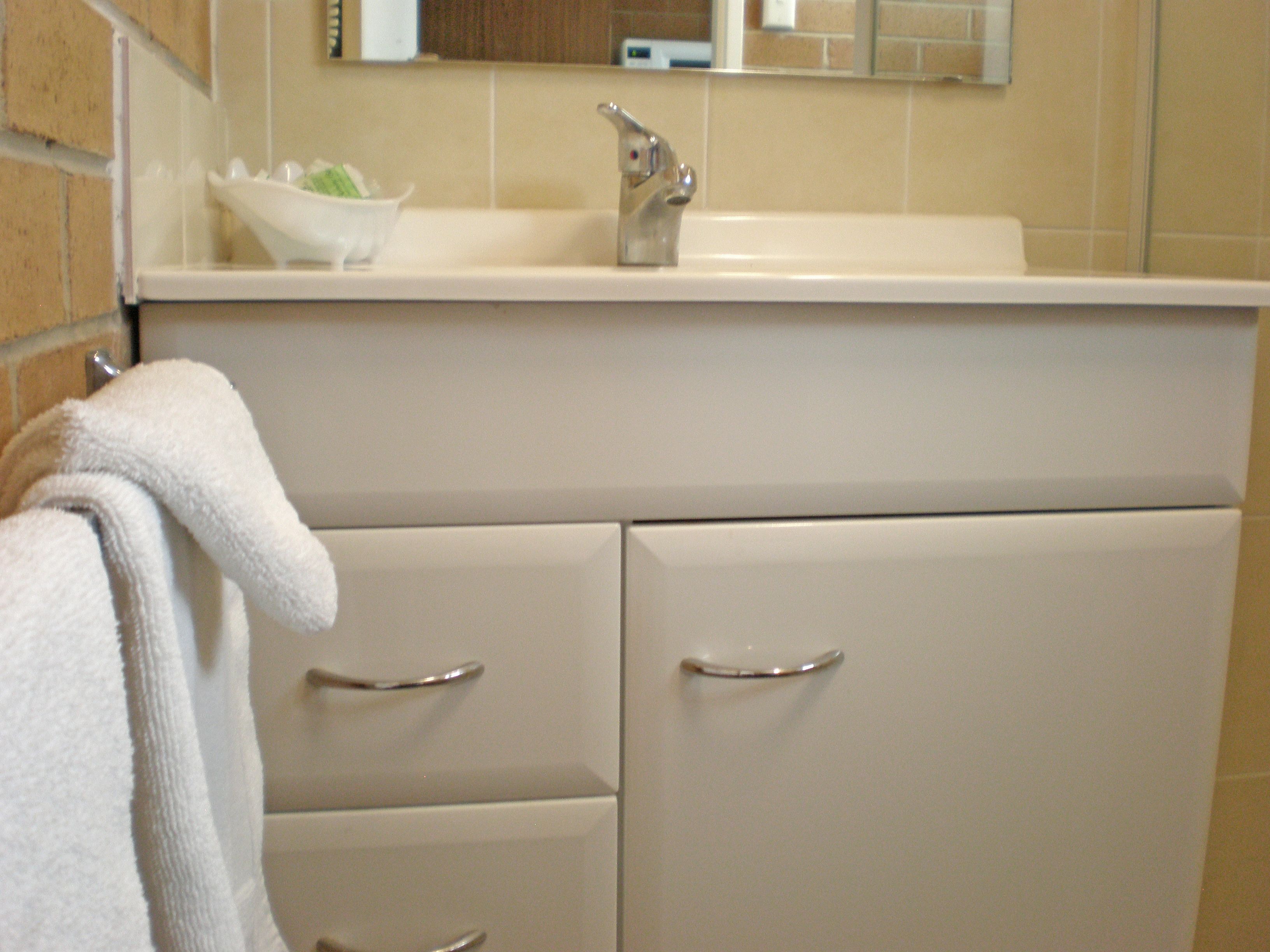 A bathroom with a sink, mirror, and two drawers.