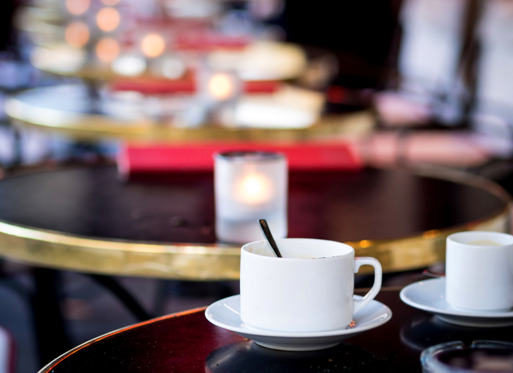 A table with two white cups and a glass, possibly containing beverages, with a blurred background suggesting a dining or cafe setting.