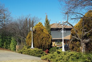 A residential house with a well-maintained lawn, a large evergreen tree, and a street lamp. - White Lanterns Motel (Armidale)