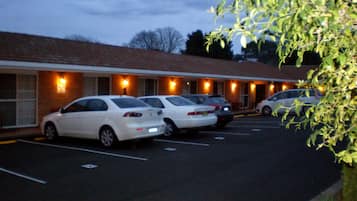 A motel with a row of parked cars and a brick building facade.