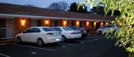 A motel with a row of parked cars and a brick building facade.