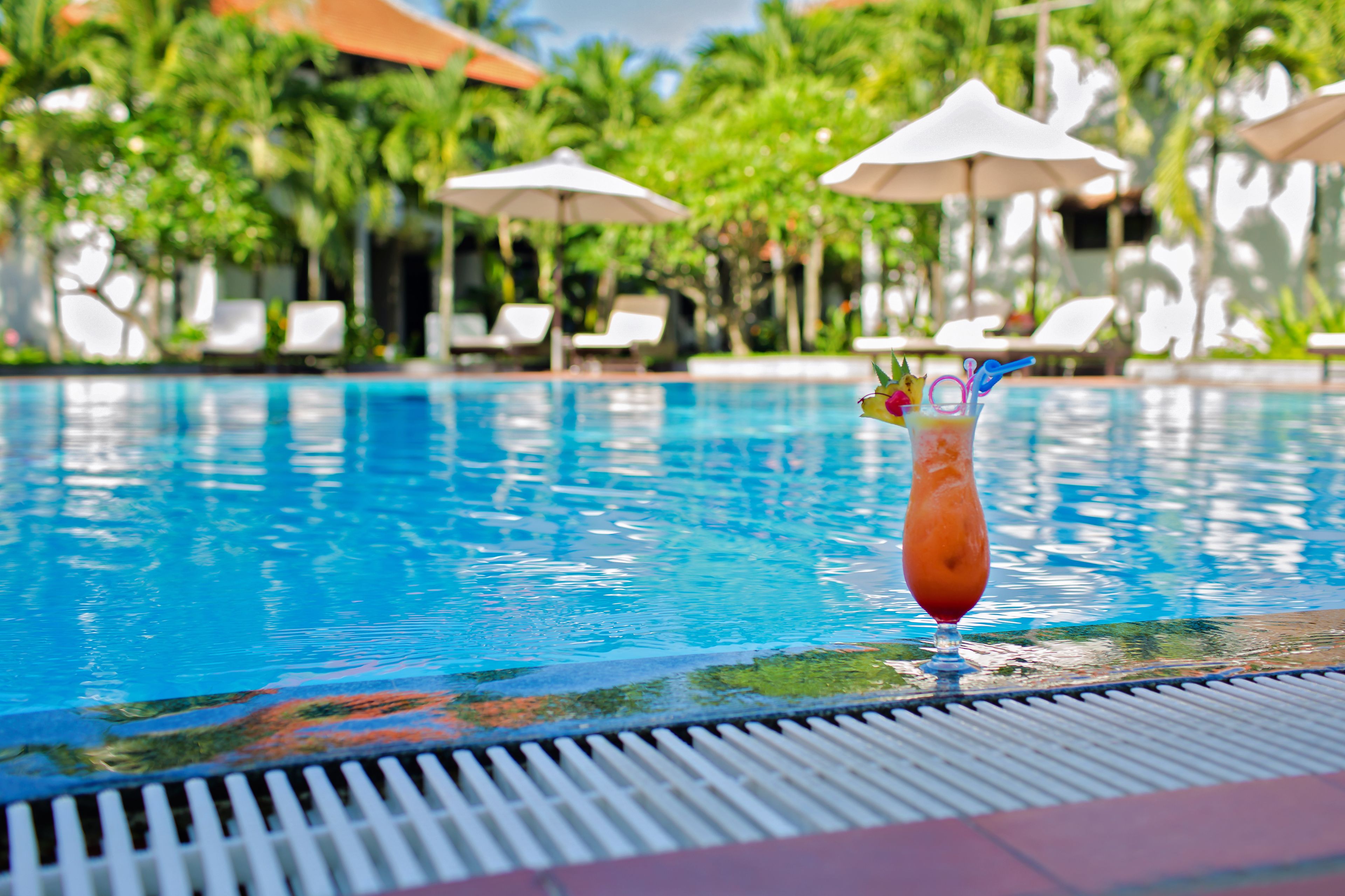 A pool with lounge chairs and umbrellas in the background.