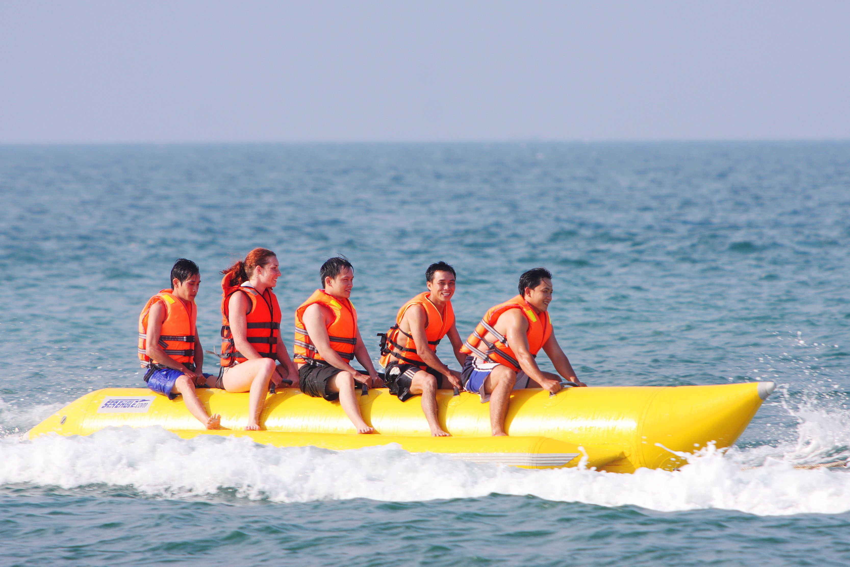 A group of people on a yellow inflatable raft in the ocean.
